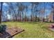 Large grassy backyard with mature trees and garden at 161 Picwyck Dr, Mooresville, NC 28115