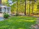 Lush green lawn with an enclosed porch, mature trees, and well-maintained landscaping at 161 Picwyck Dr, Mooresville, NC 28115