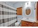 Bright bathroom with a striped shower curtain, wooden vanity, and a well-lit mirror for grooming at 161 Picwyck Dr, Mooresville, NC 28115