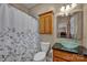 Well-lit bathroom featuring a glass bowl sink, wooden cabinetry, and a stylish shower curtain at 161 Picwyck Dr, Mooresville, NC 28115