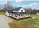White farmhouse with black roof, spacious yard, and a long driveway at 243 Reese Wilson Rd, Belmont, NC 28012