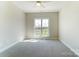 Sunlit bedroom with neutral carpet and a large window offering a view of the landscaped exterior at 3432 Greene Rd, Monroe, NC 28110