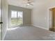 Sunlit bedroom with neutral carpet and a large window offering a view of the landscaped exterior at 3432 Greene Rd, Monroe, NC 28110
