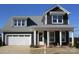 Charming two-story home featuring a white garage door, inviting front porch, and dark siding, perfect for modern living at 13618 Tranquil Day Dr, Matthews, NC 28105