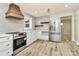 Updated kitchen with wood range hood, white cabinets and LVP flooring at 1115 218 W Hwy, Indian Trail, NC 28079