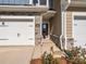 A close-up of a townhome entrance with a stone facade, dark door, and manicured landscaping at 113 Quartz Hill Way, Waxhaw, NC 28173