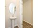 A bathroom with a pedestal sink, oval mirror, and wood-look floor at 1608 Village Grove Ln, Monroe, NC 28110