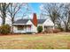 Charming white cottage with brick chimney, landscaping, and a covered porch at 402 Fisher St, Concord, NC 28027