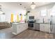 Open kitchen with white cabinets, island, stainless steel appliances, and an adjacent living area filled with natural light at 935 Mcalway Rd # 306, Charlotte, NC 28211