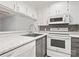 Well-lit kitchen featuring white cabinets, gray backsplash, modern appliances, and gray accent paint at 1985 Lancer Ct, Gastonia, NC 28054
