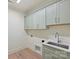 Laundry room with light green cabinets and a utility sink at 207 Audrey Place Ln, Charlotte, NC 28226