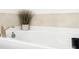 Close-up of white bathtub showing tile backsplash, brushed gold faucet, and decorative plant at 212 Portrait Way, Indian Trail, NC 28079