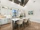 A modern kitchen features an island with bar stool seating, white cabinets, and stainless steel appliances at 212 Portrait Way, Indian Trail, NC 28079