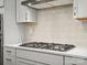 Close up of the cooktop in a kitchen with tiled backsplash and countertops at 212 Portrait Way, Indian Trail, NC 28079
