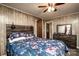 Comfortable bedroom featuring wood-paneled walls, a floral bedspread, ceiling fan and matching dresser at 2485 Nc Highway 109 S Hwy, Mount Gilead, NC 27306