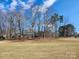 Sprawling front yard leading up to a charming brick home, framed by mature trees and a bright blue sky at 11201 Idlewild Rd, Matthews, NC 28105