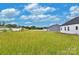 Expansive grassy backyard ready for customization and outdoor enjoyment, near modern homes under a bright, cloudy sky at 143 Tranquility Ln, Harmony, NC 28634