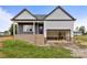New construction with gray and white siding, brick foundation and attached two car garage with visible interior construction materials at 143 Tranquility Ln, Harmony, NC 28634