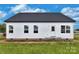 Rear exterior view of the white home, showcasing a door and a series of windows, complemented by a dark roofline at 143 Tranquility Ln, Harmony, NC 28634