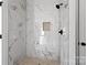 Shower with luxurious white marble tile and a built-in shower bench at 143 Tranquility Ln, Harmony, NC 28634