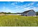 The house backyard has a long, green lawn, a white fence, and a dark-blue siding on the house at 149 Tranquility Ln, Harmony, NC 28634