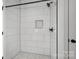 Tiled shower with glass enclosure, rain shower head, built-in niche, and pebble flooring at 149 Tranquility Ln, Harmony, NC 28634