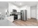 Modern kitchen featuring stainless steel appliances, white cabinets, gray counters and wood-look floors at 8024 Kennesaw Dr, Gastonia, NC 28056