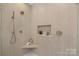 Modern bathroom shower with beige tile, and built-in shelves for storage and a hand-held shower head at 3415 Waxhaw Indian Trail S Rd, Waxhaw, NC 28173