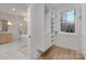 Walk-in closet features custom shelving, storage, wood floors and connects to luxurious bathroom with tub and glass shower at 3415 Waxhaw Indian Trail S Rd, Waxhaw, NC 28173