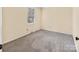 A carpeted room with natural light, featuring cream walls, white trim, and a window at 1418 Nottingham Rd, Kannapolis, NC 28081