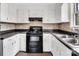 Classic kitchen featuring white cabinets, black appliances, and complementary backsplash at 1418 Nottingham Rd, Kannapolis, NC 28081