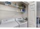 Functional laundry room with washer, dryer, and shelving for cleaning supplies at 421 N Church St # 12F, Charlotte, NC 28202