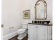 Elegant powder room with a black granite vanity, white cabinets, and an arched mirror at 3922 Ayscough Rd, Charlotte, NC 28211