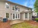 Beige two story home featuring a concrete patio with glass paned doors and various window styles at 4818 Whistling Oak Ct, Charlotte, NC 28269