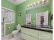 Well-lit bathroom with mint green walls featuring shower, toilet, and sink with black countertops at 15618 Frohock Pl, Charlotte, NC 28277