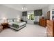 Bright bedroom with neutral carpet, ceiling fan, and large window overlooking outdoor greenery at 15618 Frohock Pl, Charlotte, NC 28277