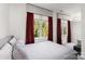 Serene bedroom featuring large windows dressed with luxurious red curtains, letting in natural light at 15618 Frohock Pl, Charlotte, NC 28277