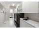 Well-organized laundry room with white cabinets, a sink, and modern black washer and dryer units at 15618 Frohock Pl, Charlotte, NC 28277