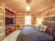 King-size bed in a rustic bedroom with log walls and built-in shelving at 2577 Dutch Rd, Mount Pleasant, NC 28124