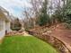 Landscaped backyard with grassy area and stone wall at 3540 Keithcastle Ct, Charlotte, NC 28210