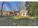 Expansive backyard with lush lawn, mature trees, and a view of the home's deck at 738 Brockbank Rd, Charlotte, NC 28209