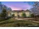 Inviting single-story home with a well-manicured lawn and mature trees, illuminated by warm lighting at 124 Muirfield Dr, Kings Mountain, NC 28086