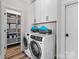 Bright laundry room with washer, dryer, storage shelves, and cabinets at 132 Rollingwood Ln, Mooresville, NC 28117