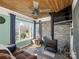 Comfortable living room with wood-burning stove and a stone wall accent, illuminated by natural light at 4465 Red Hill Cir, Denver, NC 28037