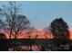 Beautiful sunset view featuring silhouettes of trees and the reflection of vibrant colors on a tranquil lake at 4465 Red Hill Cir, Denver, NC 28037