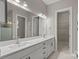 Bright bathroom featuring double vanity sinks with white cabinets, a large mirror, and access to the water closet and shower at 253 Stone Mountain Way, Denver, NC 28037