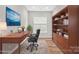 A home office with a wooden desk, bookshelf and a large monitor, staged for productivity at 253 Stone Mountain Way, Denver, NC 28037