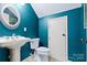 Stylish powder room featuring a pedestal sink, decorative mirror, and elegant, dark teal walls at 3317 Ritch Ave, Charlotte, NC 28206