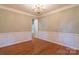 Formal dining room with classic wainscoting and hardwood floors, illuminated by an elegant chandelier at 117 Biscayne Ct, Mooresville, NC 28117
