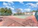 Outdoor tennis court surrounded by fencing, with beautiful cloudscape and community buildings in the background at 11735 Ridgeway Park Dr, Charlotte, NC 28277